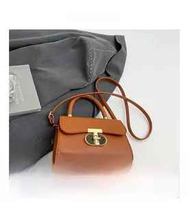 Close-up of brown leather handbag featuring a signature gold T-shaped metal lock closure
