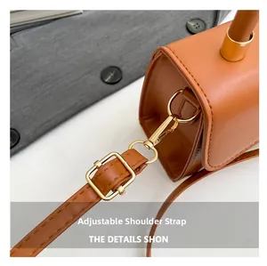 Detail view of caramel brown leather handbag with golden D-ring and adjustable strap
