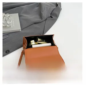 Internal capacity of brown PU leather crossbody bag showing lipstick and cushion compact