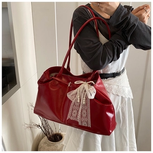 Detail of red oil wax leather tote bag with white lace bow and pearl charm on model