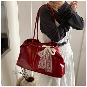Detail of red oil-wax leather tote with white lace bow and pearl charms worn on shoulder