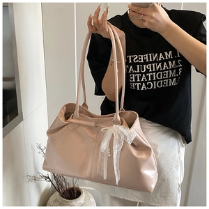 Detail of pink soft leather tote bag featuring a white lace bow and elegant pearl charm