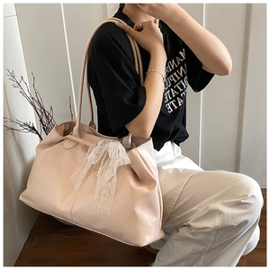 Detail of pink oil wax leather tote with a white lace bow and pearl pendant charm