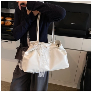 Detail of white patent leather tote bag with lace bow and pearl pendant decoration