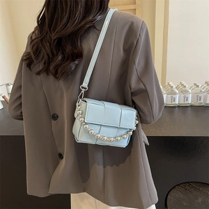 Blue woven lattice crossbody square bag with silver bead chain shown on a model