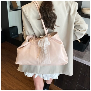 Pale pink tote bag with lace bow and pearl handle shown on a model's shoulder