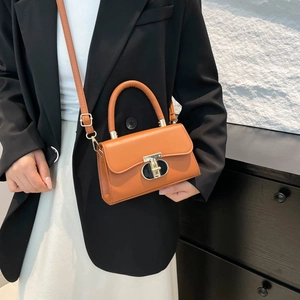 Caramel leather mini square bag with gold hardware shown as a crossbody on a black suit