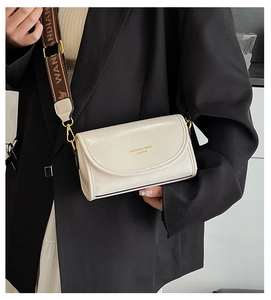Close-up of creamy white faux leather crossbody bag with wide jacquard shoulder strap