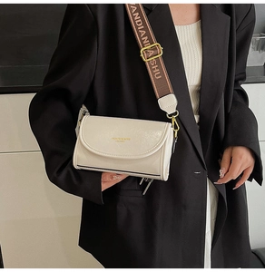 Close-up of off-white crossbody bag with wide jacquard strap and leather texture details