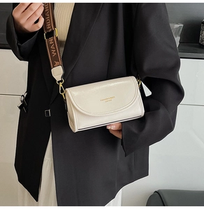 Close-up of beige leather crossbody bag with wide jacquard strap and gold hardware