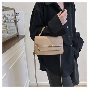 Detail of khaki leather handbag featuring a golden swivel lock and adjustable strap