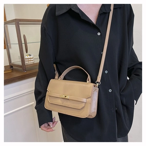 Close-up of beige leather handbag with gold twist lock and adjustable shoulder strap