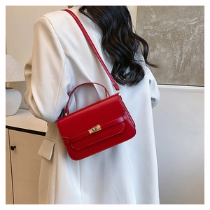 Chic red leather handbag with gold twist lock shown styled with a white blazer for women
