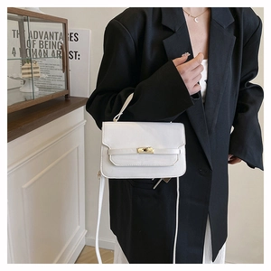 Close-up of minimalist white leather crossbody bag with a metallic twist lock on black blazer