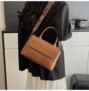 Brown crocodile pattern tote bag with wide printed fabric strap worn by a model