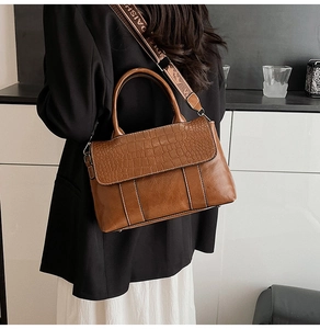 Detail of brown crocodile pattern handbag with stylish jacquard logo wide shoulder strap