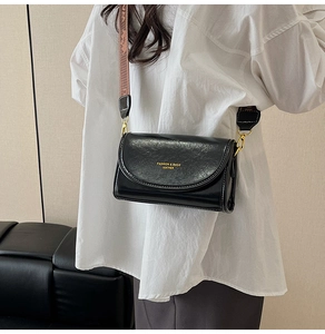 Close-up of black glossy leather crossbody bag with vintage geometric wide strap