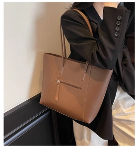 Close-up of brown tote bag with smooth texture and front zipper pocket on shoulder