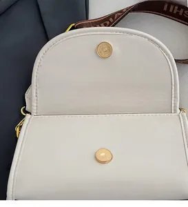 Detail of creamy white crossbody bag with lychee texture and golden magnetic closure