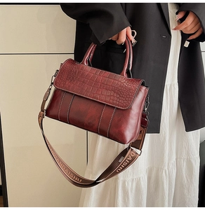 Detail of burgundy crocodile-embossed leather tote with stylish jacquard shoulder strap