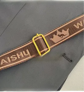 Detail of a brown woven strap with golden metal buckle and crown pattern embroidery