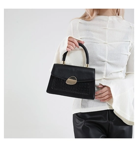 Détail du sac à main noir en similicuir avec texture crocodile et boucle en métal doré