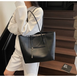 Black large capacity tote bag detail with long tassel zipper on vintage leather surface