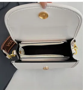 Interior view of white leather crossbody bag showing functional compartments and gold hardware