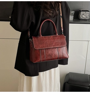 Dettaglio borsa bordeaux motivo coccodrillo con tracolla jacquard indossata da modella