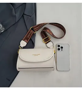 Detail view of cream leather crossbody bag with wide jacquard strap and size comparison