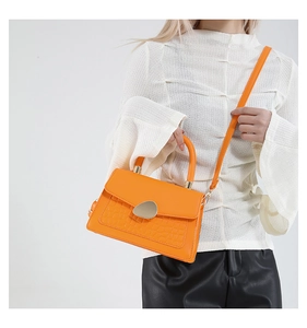 Détail du sac à main orange avec texture crocodile, fermoir doré et bandoulière réglable