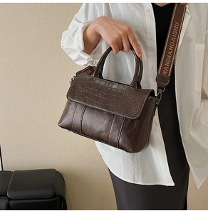 Detail of dark brown faux crocodile tote bag with contrasting white stitching and strap