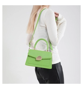Détail du sac vert néon en similicuir avec texture croco et boucle dorée galet