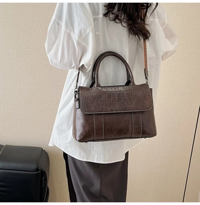 Detail of dark brown faux leather tote with crocodile texture flap and wide strap