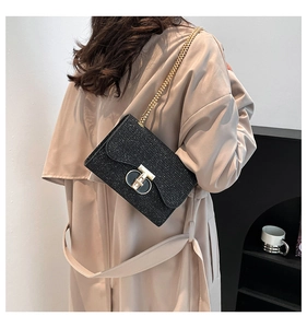 Détail du sac bandoulière noir à paillettes avec fermoir en T doré et bandoulière chaîne