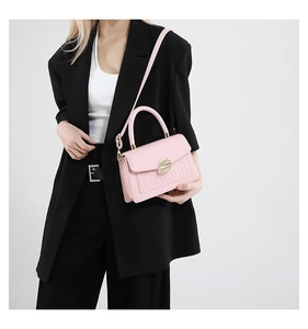 Détail du sac en similicuir rose avec texture crocodile et boucle dorée ovale