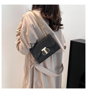 Détail du sac à chaîne pailleté noir porté avec un trench-coat beige tendance