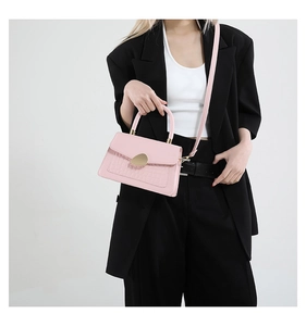 Détail du sac rose avec effet crocodile, boucle dorée et poignée élégante de mode