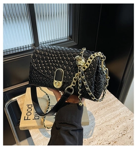 Détail de la texture en cuir tressé et du fermoir doré sur un sac à bandoulière noir
