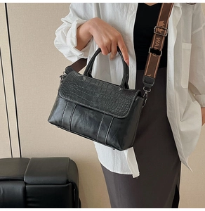 Borsa a mano nera effetto coccodrillo con ampia tracolla in tessuto indossata da modella