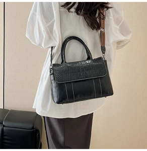 Dettaglio della borsa con patta coccodrillo e tracolla larga a motivi trendy