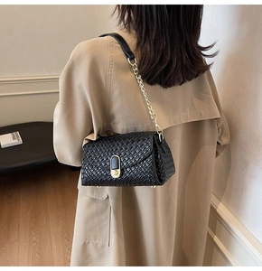 Détail d'un sac à main tressé noir avec bandoulière chaîne dorée et fermoir en métal