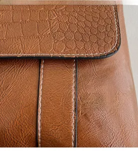 Dettaglio della borsa in ecopelle marrone con stampa coccodrillo e cuciture a vista