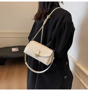 Détail du sac oreiller tissé blanc cassé avec chaîne dorée et boucle en métal