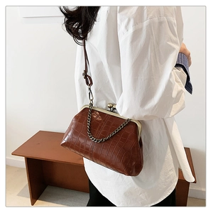 Detail of caramel brown crocodile-patterned crossbody bag with vintage bronze clasp