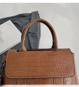 Dettaglio borsa marrone trama coccodrillo con cuciture bianche e manico rotondo