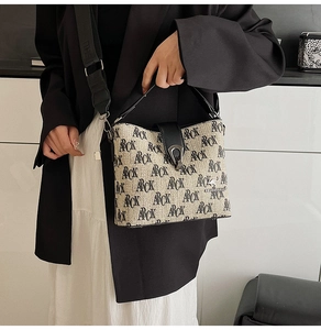 Close-up of printed canvas bucket bag with black leather handle and metal clasp buckle