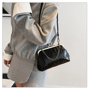 Detail of glossy black crocodile embossed leather and vintage bronze kiss-lock closure