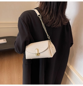 Détail du sac tressé crème avec fermoir doré et bandoulière en chaîne de cuir
