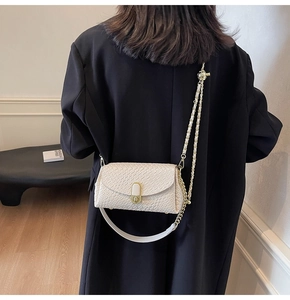 Détail du sac oreiller blanc cassé avec chaîne dorée et fermoir métallique sur mannequin